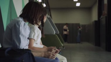 Okulun koridorunda iki neşeli kız ellerinde akıllı not defteriyle. Tabletli meraklı kızlar öğrencilerin iletişim kurmasını izliyor. Çeşitli enerjik öğrenciler koridorda mola veriyor..