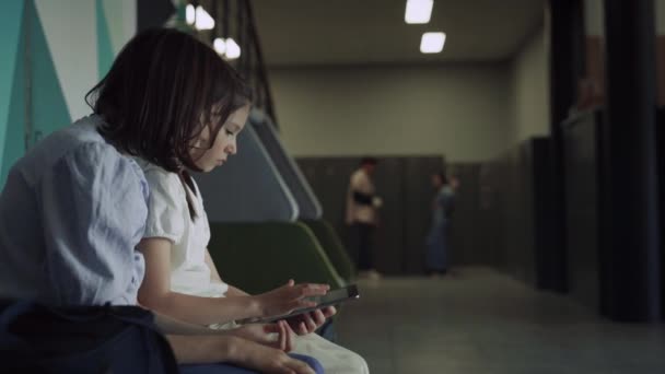 Two Serious Schoolgirls Scrolling Tablet Computer Sitting School Hall Curly — Stock Video