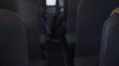 Okul otobüsünde oturan çok ırklı çocuklar yakın çekim bekliyor. Odaklanmış Afrikalı Amerikalı kız gün ışığında kitap okuyor. Şirin, gülümseyen kıvırcık çocuk arkadaşlarını selamlıyor. Araç taşımacılığındaki çeşitli reşit olmayan çocukları göster