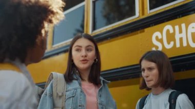 Sarı okul otobüsünde duran üç kız yaklaşıyor. Çeşitli okul çocukları güneşli bir sabahtan bahsediyor. Kıvırcık Afrikalı Amerikalı liseli kız dışarıda arkadaşlarıyla iletişim kuruyor. Eğitim kavramı.