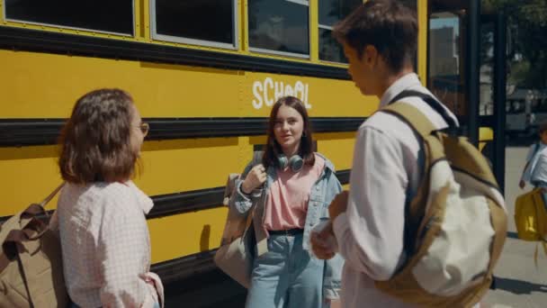 Усміхнені Студенти Стоять Разом Розмовляючи Жовтому Шкільному Автобусі Веселі Школярі — стокове відео