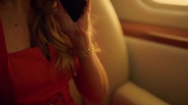 Kendine güvenen patron iş gezisinde akıllı telefondan konuşuyor. Muhteşem bayan özel jetle seyahat ediyor. Zengin gülümseyen iş kadını lüks bir uçakta cep telefonuyla konuşuyor. Zengin yaşam tarzı konsepti.