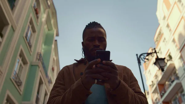 重点男子使用智能手机步行街的肖像 社交网络的概念 严重英俊的非洲裔美国人独自去发短信的朋友伴侣 应用程序客户读新闻留声机 — 图库照片
