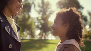 Gülümseyen ebeveyn, altın güneş ışığı portresindeki güzel kızıyla burunlarına dokunuyor. Mutlu Afro-Amerikan kadın. Koşulsuz sevgi desteği veren nazik anne. Duygusal bağ tasasız çocukluk.