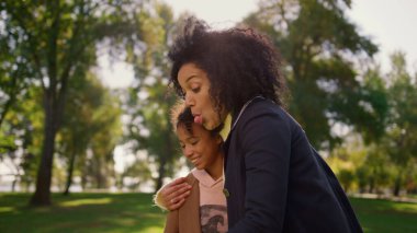 Parkta güzel bir kızla komik bir selfie çeken mutlu bir anne. Neşeli Afro-Amerikalı kadın aile pikniğinden zevk alıyor. Dışarıda gülümseyen kıvırcık çocuk. Anneler Günü konseptini kutlamak