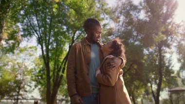 Portre seven baba gülümseyen kızı kucaklıyor ve birbirine yeşil parkla bakıyor. Gülümseyen Afro-Amerikan erkek şefkatli baba dışarıda sevimli kız çocuğu pozu veriyor. Duygusal bağ tasasız çocukluk