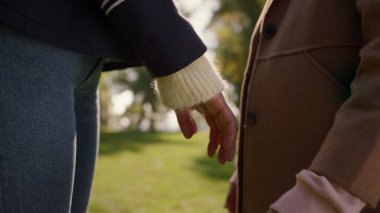 Sunny Park 'ta el ele tutuşan anne kızı. Yakın çekim. Mutlu anne çocuğu. Tanımlanamayan Afro-Amerikan kadın ebeveyn kızın ellerine hafifçe dokunarak sevgisini ifade ediyor. Aile bağı kavramı.