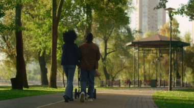 Sunny Park 'ta bebek arabasını yan yana iten ebeveynler. Mutlu ebeveynlik zamanları. Bilinmeyen bir çift yeni doğmuş bebekle yeşil yolda rahatlıyor. Kaygısız anne baba eğleniyor.