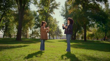 Güneşli bir günde tatlı kızıyla sabun köpüğü üfleyerek rahatlatan anne. Güzel Afro-Amerikalı kadın gülümseyen çocukla oynayıp hava toplarının uçuşunu seyrediyor. Aile hafta sonu açık hava konsepti