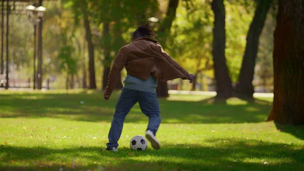 Man playing soccer park on warm spring day. Focused player practicing outdoors. Playful african american man father doing football tricks enjoying game weekend. Active hobby healthy lifestyle concept.