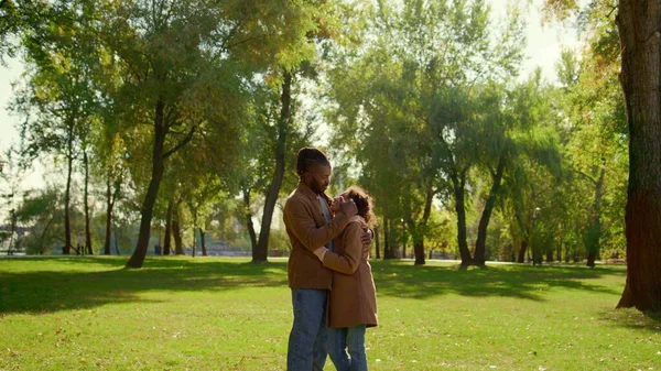 Gülümseyen ebeveyn kızı nazikçe çocuğa dokunuyor. Koşulsuz baba sevgisi. Yakışıklı Afrikalı Amerikalı baba mutlu çocuğu kucaklıyor ve parkta eğleniyor. Ebeveynlik duygusal bağlılık kavramı.