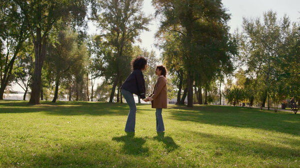 Mother holding daughter hands gently touching noses on sunny green park field. Happy african american family enjoying time together express unconditional love. Emotional connection between child mom.