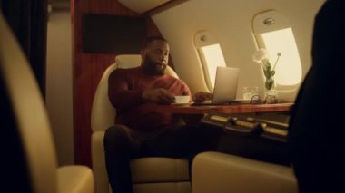 Başarılı bir adam iş gezisinde dizüstü bilgisayarda çalışıyor. Afrika kökenli Amerikan CEO 'su kahve içiyor. Tatil uçuşu raporlarını kontrol ediyor. Odaklanmış sakallı adam internette sohbet ediyor.