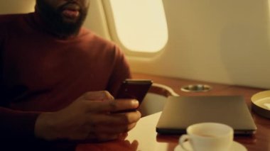 Mutlu girişimci iş seyahatinde arkadaşını arıyor. Gülümseyen adam konuşuyor. Uçak penceresinde hareketli konuşmalar yapıyor. Başarılı Afro-Amerikan CEO 'su lüks jetle seyahat ediyor.