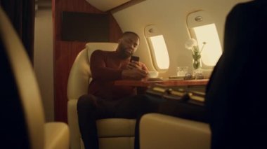 Birinci sınıfta internete göz atan mutlu bir adam. Neşeli yolcu uçak penceresinde akıllı telefonuyla kahve içiyor. Zengin Afro-Amerikan işadamı şirket gezisinde sosyal medyanın tadını çıkarıyor..