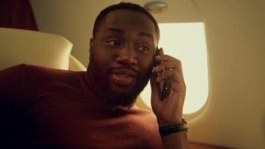 Pozitif iş adamı, iş ortağı ile yakın planda akıllı telefon konuşuyor. Mutlu Afro-Amerikan erkeği birinci sınıfta seyahat etmekten zevk alıyor. Sakallı CEO başarılı şirket anlaşmasını tartışıyor..