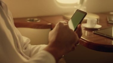 Krom tuşlu akıllı telefonları kapatan eller. Bilinmeyen bir adam iş gezisinde ekran görüntüsü aşırıyor. Rahat zengin yolcu cep telefonuyla sosyal medya iş e-postalarını kontrol ediyor. Tatil gezisi konsepti.