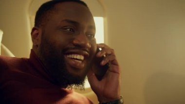 Uçağın penceresinde konuşan Afro-Amerikan cep telefonu. Birinci sınıf bir adam telefon konuşmasından zevk alıyor. Güvenilir CEO dinlenme jeti. İş teknolojisi kavramı.