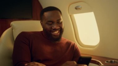 Neşeli adam uçak penceresinde arkadaşına mesaj atıyor. Mutlu iş adamı yayın platformunu izlemekten zevk alıyor. Afro-Amerikan adam dinleniyor. Cep telefonuna bak. Tatil uçuşu kavramı