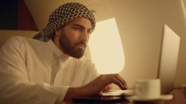 Bilgisayarı daktilo eden odaklanmış bir adam. Başarılı bir profesyonel web tarayıcı sorunu. Ciddi bir Arap yöneticisi geleneksel kıyafetle internette sohbet raporlarını analiz ediyor. İş seyahati kavramı.