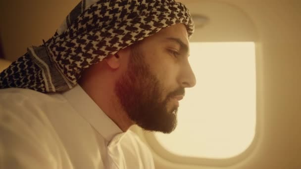 成功したビジネスマンは飛行機を閉鎖した ウィンドウでコーヒーを飲んで休んでいる幸せなアラビア人男性 自信を持って財務アナリストの最高経営責任者 Ceo 伝統的な衣装で出張をお楽しみください ラグジュアリーライフスタイルコンセプト — ストック動画