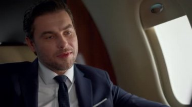 İş gezisinde gülümseyen CEO konuşması. Uçak penceresindeki video konferansında başarılı bir yönetici sohbet partneri. Neşeli yolcu takım elbiseli sohbetin keyfini çıkar. Kendine güvenen profesyonel bir erkek.