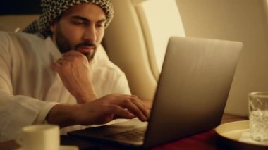 İş gezisinde laptopta çalışan düşünceli müslüman. Uçak penceresinde şirket istatistiklerini analiz eden zengin bir adam. Kendine güveni tam bir iş adamı, geleneksel kıyafetler içinde bir proje düşünüyor..