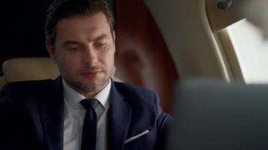 İş gezisinde kahve içen, bilgisayar görünümlü bir iş adamı. Rahat ve yakışıklı finans müdürü takım elbise içinde internet gezintisinin tadını çıkarıyor. Başarılı yolcu içecek için yudumlama laptopu kullan