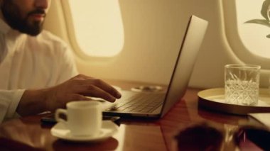 Kendine güvenen lider yakın planda dizüstü bilgisayara bakıyor. Tuş takımını kullanarak şirket gezisinde çalışan odaklanmış Arap iş adamı. Başarılı şirket sahibi, Müslüman kıyafetiyle internette lüks bir sörf yapıyor..