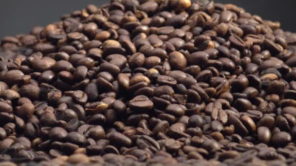テクスチャコーヒー粒の背景を閉じます 超スローモーションでローストブラウンの種から来る軽い芳香の蒸気 濃い背景に新鮮なオーガニックコーヒーヒープ カフェイン飲料の原料 — ストック動画