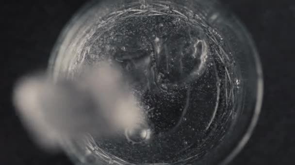 手はきれいな輝く水を閉じてガラスに氷のキューブをスローします 黒い表面の容器からゆっくりとした動きできれいなアクアが飛び散った 冷たいミネラルドリンクの上ビューマクロ カクテルをコンセプトに — ストック動画