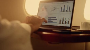 Eller dijital bilgisayarda çalışıyor. Yönetici uçaktaki şirket grafiklerini kontrol ediyor. Tanınmayan iş adamı dizüstü bilgisayardaki raporları analiz ediyor. Şirket iş seyahati konsepti.