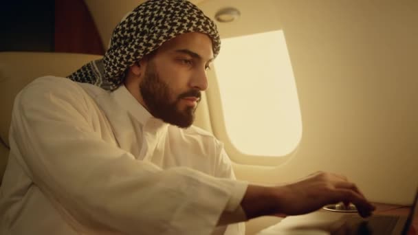 微笑的商人在喷气机特写上了笔记本电脑 成功的男人在电脑上浏览网页 成功的阿拉伯聊天在线发送消息 商务旅游飞机上漂亮的冲浪运动 — 图库视频影像