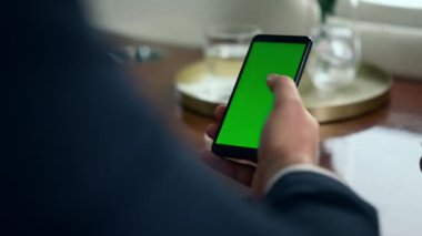 El ele tutuşan krom anahtarlı akıllı telefon. Yönetici şirket uçuşunda çalışan yeşil ekrana dokunuyor. Tanımlanamayan şirket CEO 'su takım elbise içinde model cihazı kullanıyor. İş teknolojisi kavramı.