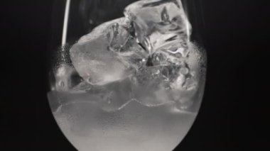 Soğuk su buz küpleri cam, yakınlaştır. Yoğunlaştırılmış şarap kadehi ağır çekimde buzlu antioksidan soda. Soğuk, köpüklü içecek, siyah arka plan. Dondurulmuş tonik konsepti
