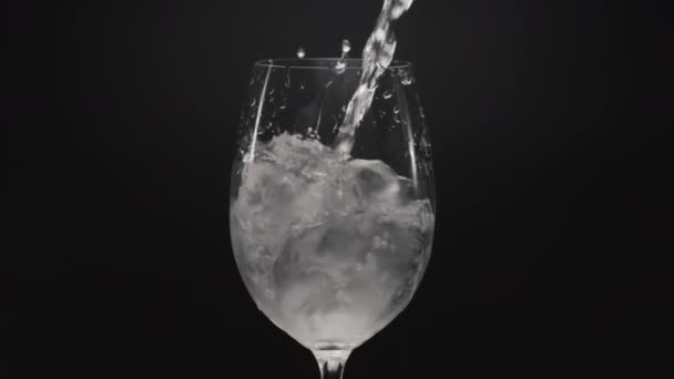 喷水浇灌冰玻璃窗特写 在透明的玻璃中闪烁着清澈的气泡液体和冰块 带空气的松软矿泉水冒出黑色背景 拟订鸡尾酒概念 — 图库视频影像