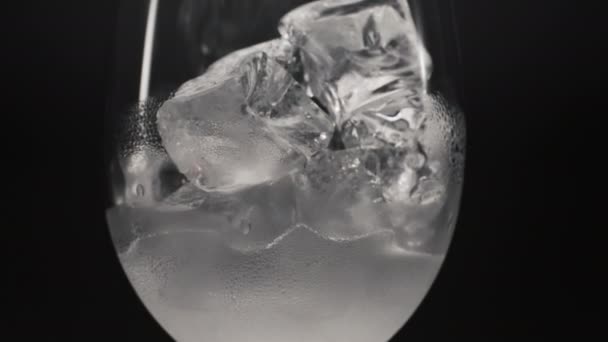 冷水冰块使玻璃特写放大 含冰块的抗氧化剂苏打水在冷凝水中慢动作 清凉清澈的气泡饮料黑色背景 冷冻补品的概念 — 图库视频影像