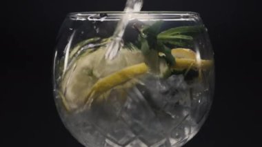 Limonlu naneli şarap kadehini dolduran jet suyu. Şifalı bitkiler ve limonlu soda kokteyli. Köpüklü limonata kokteyli siyah arka plan görüntüsü. Ev yapımı içecek konsepti hazırlanıyor