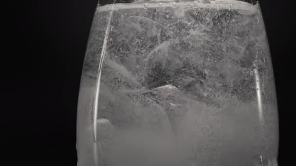 冰块起泡的水杯特写 清澈清澈的温格拉斯慢动作中闪耀的饮料 空气滴在黑色液体背景内移动 更新补品鸡尾酒概念 — 图库视频影像