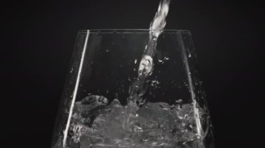 Buzlu su, şarap kadehini yakınlaştırıyor. Şeffaf camlarda buz küpleri olan berrak bir sıvı. Hava damlaları siyah arkaplan olan mineral su. Canlandırıcı kokteyl konsepti hazırlanıyor
