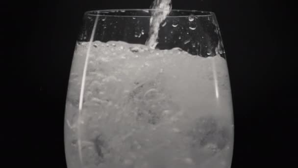 发泡的水倒入冰醋栗特写 喷出清爽的气泡液体 用冰块填满透明的杯子 有黑色底色的矿泉水 拟订鸡尾酒概念 — 图库视频影像