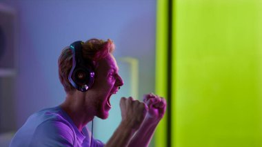 Heyecan verici kazanan maç galibiyetini yakından kutluyor. Mutlu adam neon siber uzay stüdyosunda siber turnuva kazandı. Duygusal kızıl adam Esport şampiyonasında online zaferin tadını çıkarıyor. Zafer anı konsepti.
