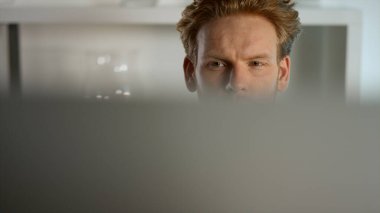 Ofiste çalışan yakın plan odaklı bir adam. Dalgın yönetici verileri kontrol ediyor. Odaklanmış zencefil işadamı, odağını kaybetmiş monitörün arkasındaki proje kayıtlarını inceliyor. Öğrenci sörf interneti