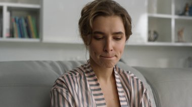 Düşünen kadın oturma odasındaki kanepede dinlenmeyi düşünüyor. Sinirli kız arkadaş, akıllı telefonu sosyal medya uygulamasında mesaj göndermek için kullanıyor. İlişki krizi kavramı.