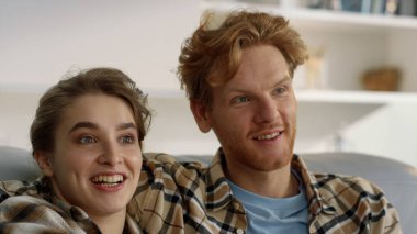 Mutlu aile komedi filmi izleriz. Oturma odasında birlikte iyi vakit geçiririz. Kızıl saçlı güzel kadın konuşuyor. Kanepede şaşırmış bir ifadeyle sarılıyor. Aşk çifti evde eğlenceli video bloglarının keyfini çıkarıyor.