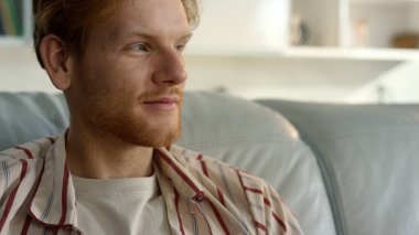 Gülümseyen adam hafta sonu tek başına dinleniyor. Düşünceli kızıl adam pijamalarıyla sabah dingin atmosferinin tadını çıkarıyor. Rahat milenyum işadamı rahat kanepeye bak. Tatmin olmuş serbest çalışan, kanepeye yaslanmış.