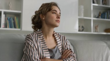 Pijamalı, üzgün kız sorunlarını yakından düşünüyor. Güzel bir bayan hafta sonu kanepeye poz veriyor ve yalnız başına dinleniyor. Evdeki kişisel sorunları göz önüne alan dalgın bir bayan. Kişisel izolasyon kavramı.