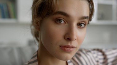 Güzel kız eve yakın poz veriyor. Doğal makyajlı, kusursuz ciltli güzel sarışın bayan. Rahat öğrenci kız arkadaş sakin bir sabah atmosferinin tadını çıkar. Nazik güzellik blogcusu kamerayı koltukta dinlendiriyor.