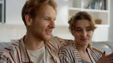 Genç aşıklar evde pijamalarıyla konuşuyor. Mutlu insanlar huzurlu bir sabah geçirmenin tadını çıkarırlar. Neşeli kızıl erkek koca, yeni evinde çekici eşine sarılıyor. Gülümseyen aile hafta sonu oturma odasında dinleniyor.