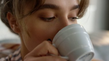 El ele tutuşup kahve fincanını yakın plan çekelim. Rahat kız kanepede sabah içkisinin tadını çıkarıyor. Çekici sarışın eş kahvaltı saatinde sıcak çay tadıyor. Bir yudum alan güzel kadın cennet gibi bir hafta sonu başlıyor.